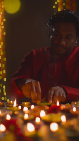 Vertical-Video-Shot-Of-Man-Lighting-Diya-Oil-Lamps-Celebrating-Festival-Of-Diwali-In-Slow-Motion